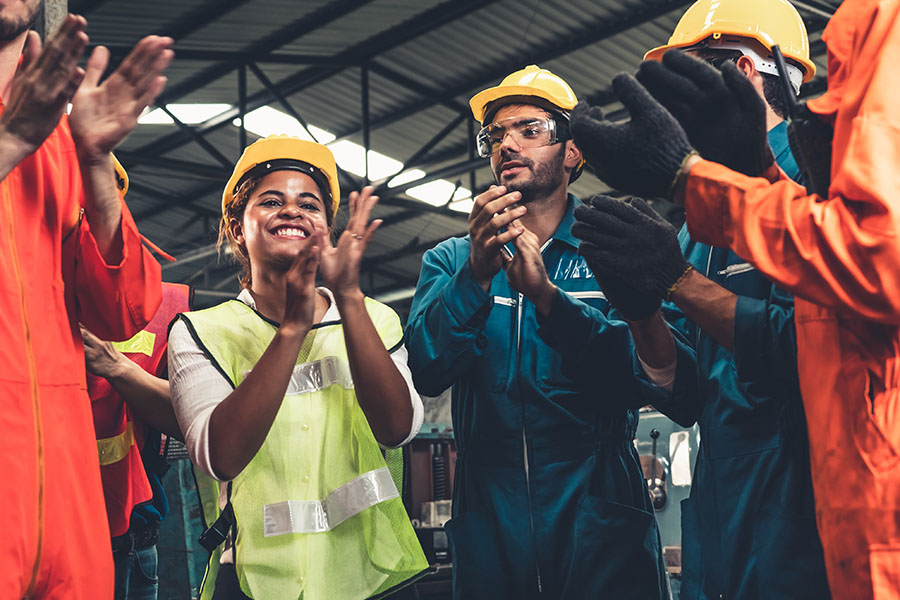 Specialized Business Insurance - Closeup Portrait of a Cheerful Group of Factory Workers Standing in a Circle While Clapping Their Hands to Celebrate Success